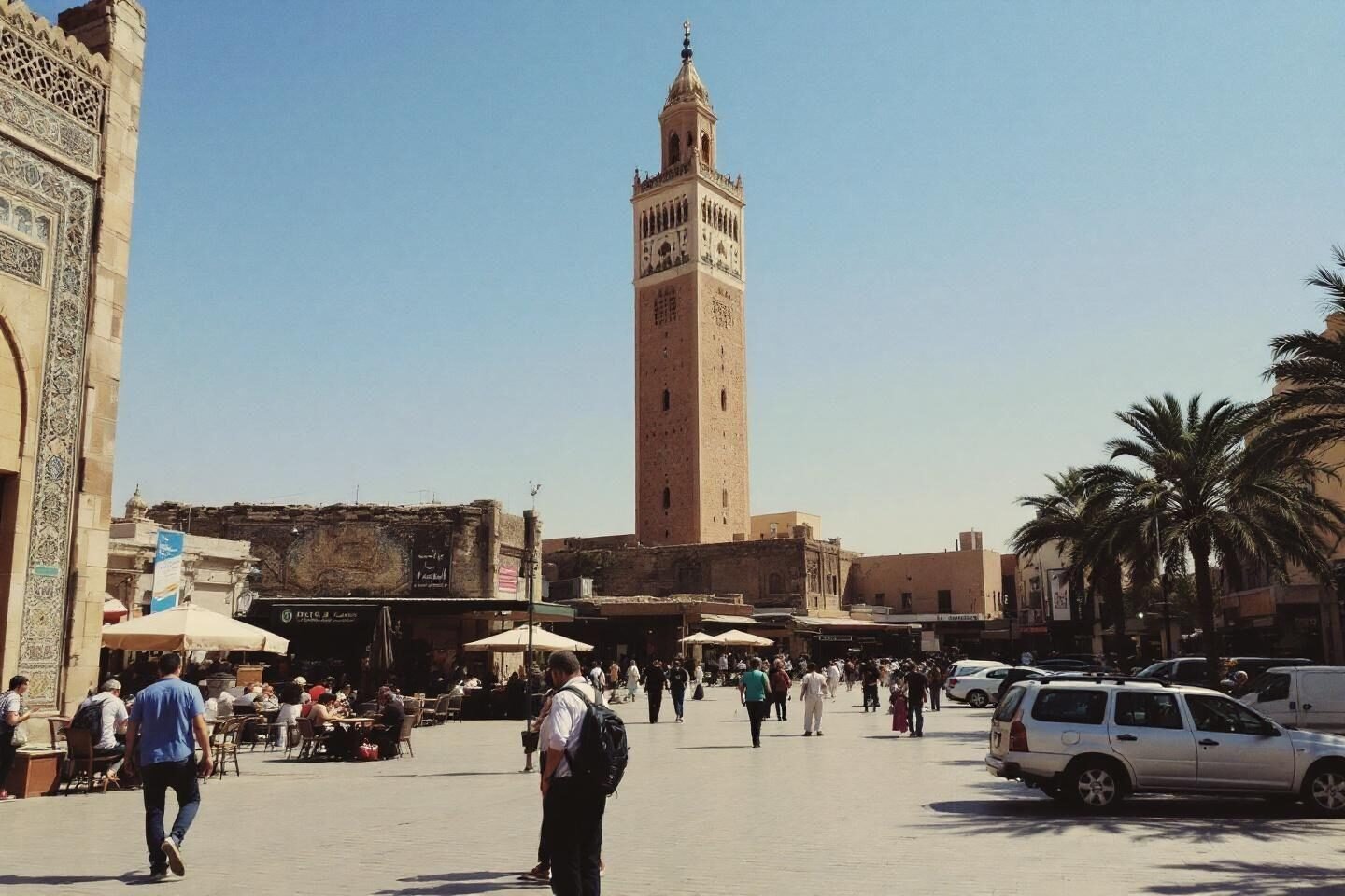 Historic Islamic tower with people walking in sunny square