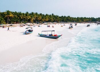 White sandy beach, turquoise waves, palm trees, traditional boats