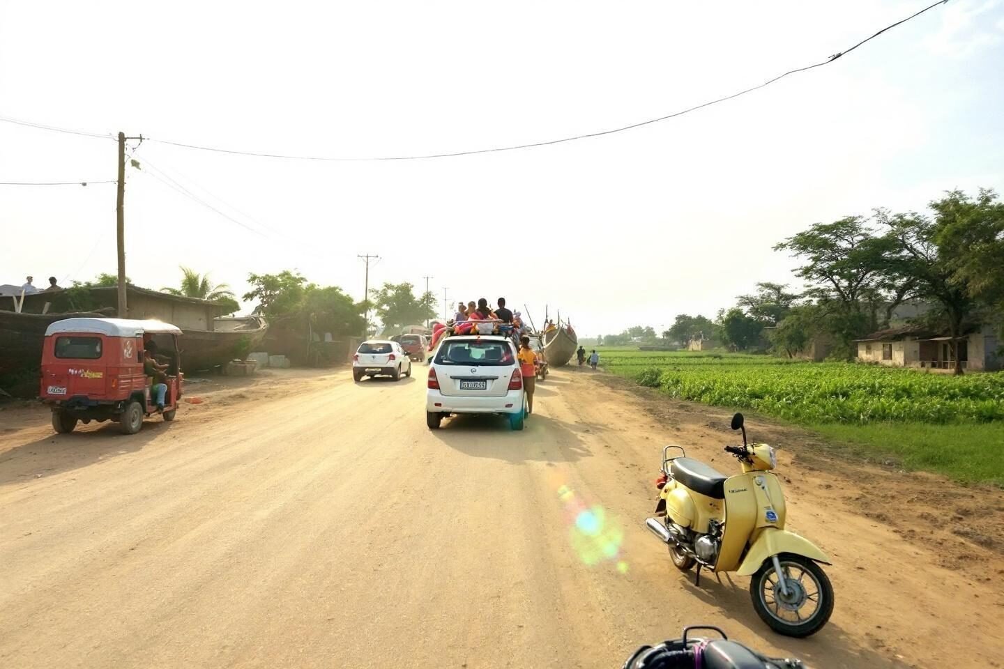 Vehicles on dirt road with fields and utility poles
