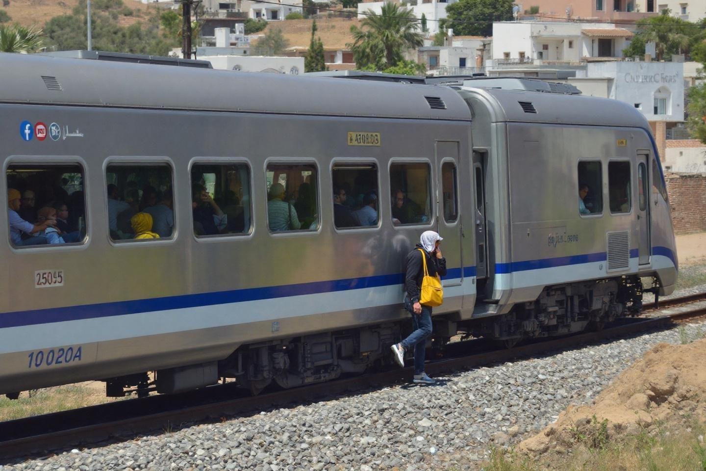 Complete guide to travel around Morocco with KiwiTaxi : airports, cities, and hotels Train stopped on tracks with passenger standing next to carriage