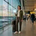 Woman with luggage checking phone at airport departure gate