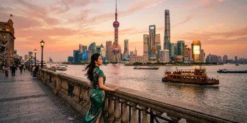 Woman in green dress overlooking Shanghai's illuminated skyline at sunset
